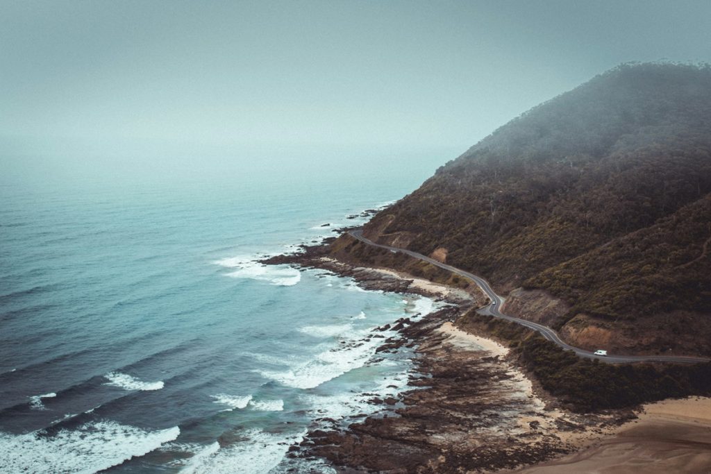 strada costiera in Australia con l'oceano da un lato e le montagne dall'altro